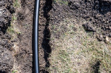 Sığ bir sipere yerleştirilmiş 1 inçlik siyah bir fıskiye su borusuna odaklan.