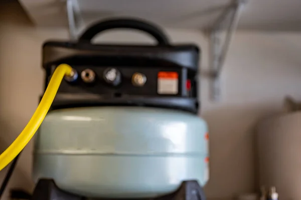 Selektiver Fokus auf Schlauch, der zu einem Pfannkuchen-Luftkompressor führt, der auf einem Regal sitzt — Stockfoto