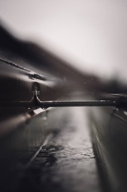 Kasırga sırasında su taşıyan bir hangarla iskan oluğunun seçici bir kısmına odaklan. Yağmur damlaları ve damlalar görünür.