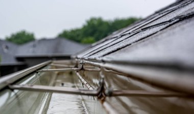 Selective focus on a section of residential guttering with hanger conveying water during a storm. Rain splatters and drops visible. clipart