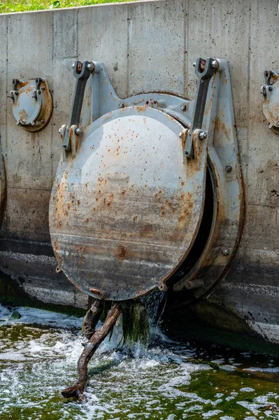 Heavy metal flood control gate discharging into a waterbody — Stock Photo, Image