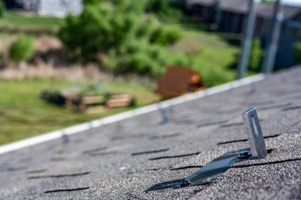 집에 있는 아스팔트 지붕에는 태양열 패널 레일 과 레이킹 시스템을 설치하기 위해 설치 된 금속 앵커가 설치되어 있다 — 스톡 사진