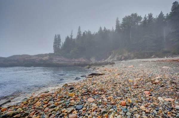 Meerkleurige ronde rotsen op Little Hunters Beach in Acadia National Park, Maine. Getij komt binnen als golven crashen. — Stockfoto