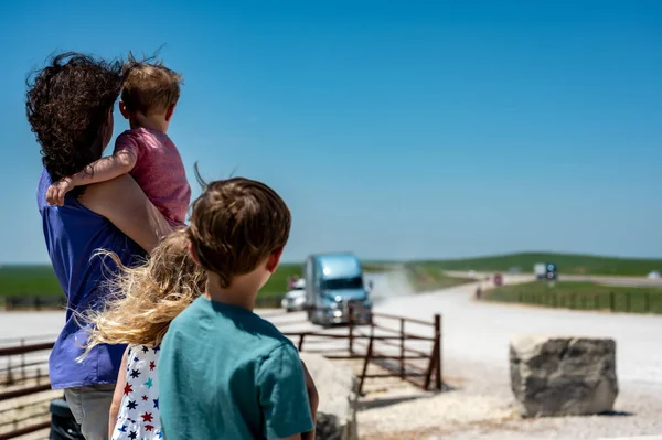 Anne ve çocuklar uzaklara bakarken bir tır yolda ilerliyor.