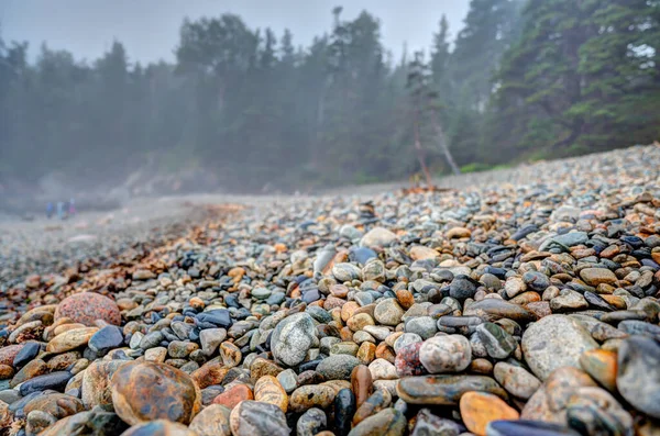 Multi-barevné kulaté skály na Little Hunters Beach v národním parku Acadia, Maine. Přichází příliv a vlny se hroutí. — Stock fotografie