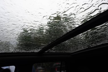 Aracın içinde su damlacıkları olan bir çatıya bakıyoruz. 