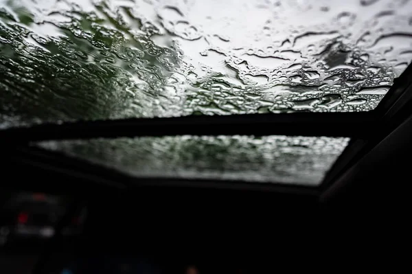 Dentro de un vehículo mirando hacia un techo solar con gotitas de agua — Foto de Stock