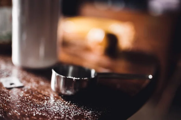 컵의 치수와 설탕의 알갱이들이 있는 흐린 부엌 식탁 위 — 스톡 사진