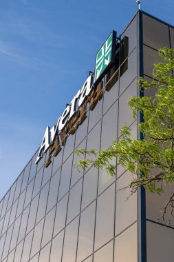 Sioux Falls 'da, üzerinde Avera Sağlık tabelası olan modern bir cam bina bulunuyor. Gökyüzü açık ve ön planda ağaç yaprakları görülebiliyor. Huzurlu bir manzara yaratıyor..