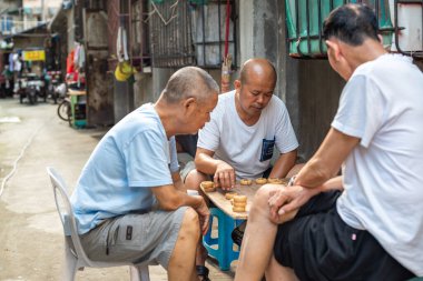 Üç kıdemli Çinli sokakta Çin satrancı oynuyor.