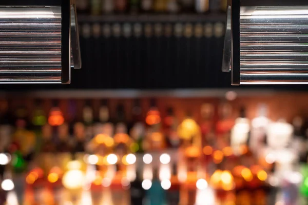 Rozostřený bar počítadlo s podsvícenými lahvemi v pozadí — Stock fotografie