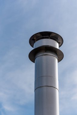 Mavi gökyüzüne karşı çelik baca alçak açı görünümü