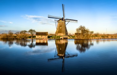Windmill reflecting in water in Netherlands clipart