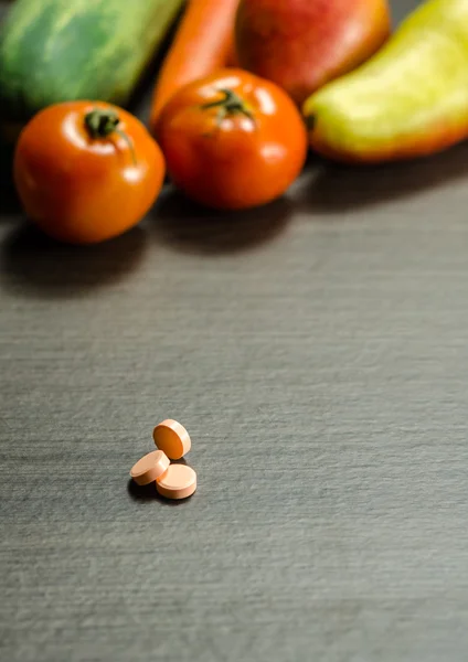 Medicin tabletter med färgglada grönsaker på bakgrund — Stockfoto