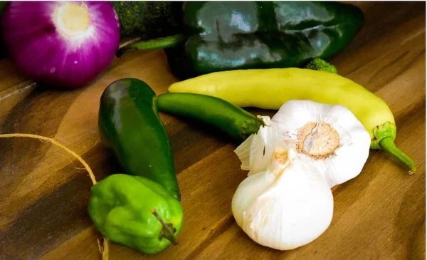 Tahta bir masada soğan sarımsak ve kırmızı biber.