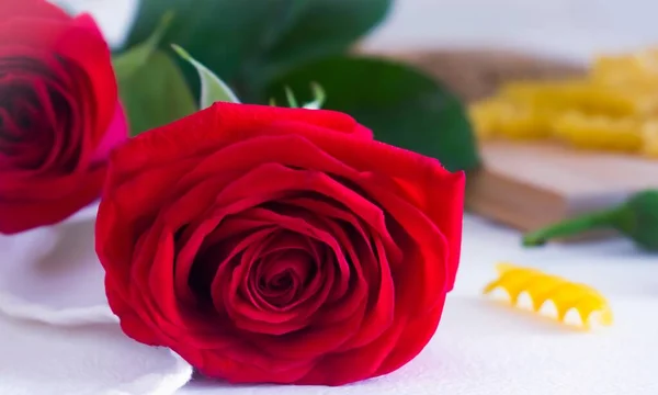 Kırmızı gül, makarna, kırmızı biber ve kesim tahtası.