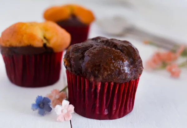Çikolatalı kek ve beyaz bir masada üç çiçek.