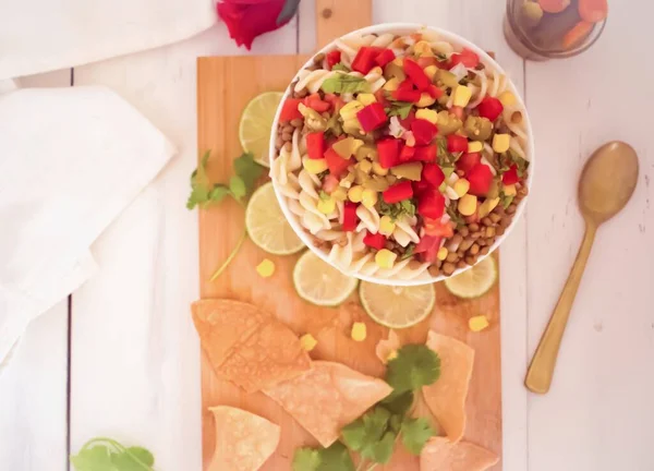 lentil salad with pasta and red rose, on vegetable chopping board