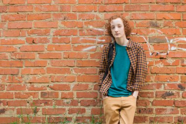 Genç bir adamın portresi kırmızı tuğladan bir duvara karşı..