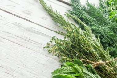 Metin için boş alan. Bir demet biberiye, nane, kekik, beyaz ahşap bir masada dereotu.