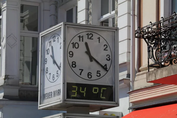 Zaman ve sıcaklığı gösteren kamusal alanda kare saat. Metnin çevirisi: yeni pazar (Neuer Markt karenin adıdır)
