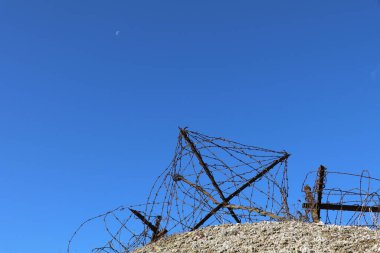 Fransa 'da korunmuş savaş siperlerinin tepesinde eski paslı dikenli teller, açık mavi gökyüzü