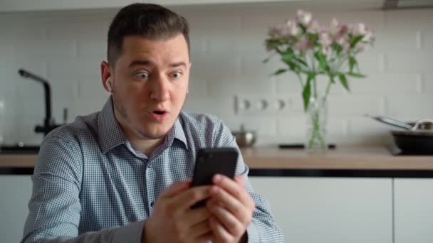 Hombre Emocionado Mirando Teléfono Inteligente Casa Feliz Adulto Joven Caucásico — Vídeo de stock