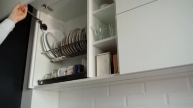 Tanımlanamayan bir adamın eli mutfak cephesini açıyor. Modern beyaz mutfağın çekmecesini çekip kapatan bir adam.