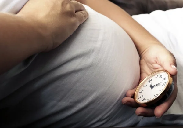 Schwangerschaftsbauch und tickende Uhr in Mamas Hand — Stockfoto