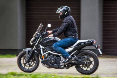 Motosikletli biri şehirde motosiklet sürüyor.