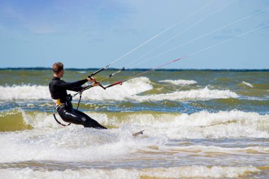 Uçurtma sörfçüsü soğuk Baltık denizinin dalgalarında yüzer.