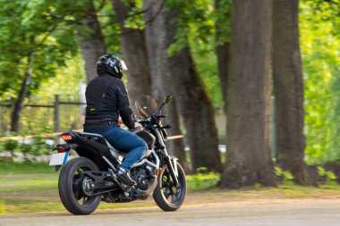 Motosikletli şehir parkında motosiklet sürüyor.