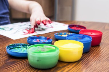 Mutlu çocuk elleri boyalı resim çizer.