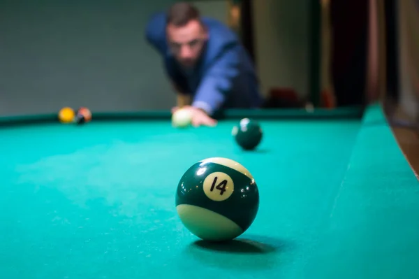 Bilardo oyuncusu 14 numaralı yeşil topa nişan aldı ve bir yumruk attı.
