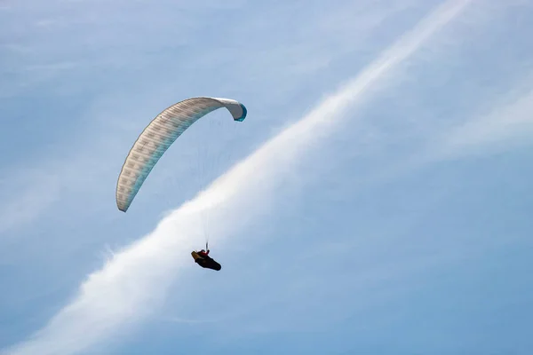 Mavi gökyüzünde bulutlarla uçan beyaz paraglider
