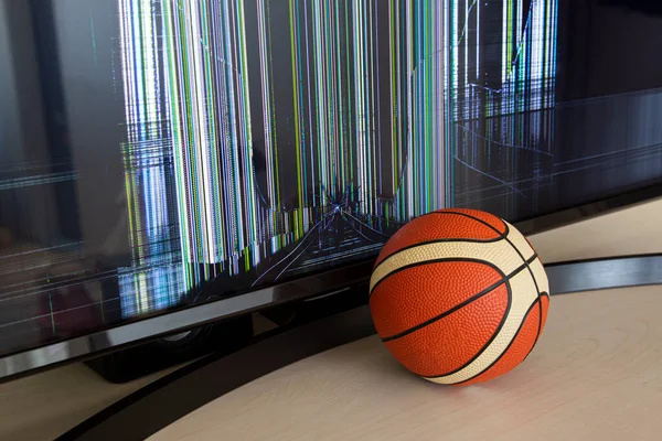 Bir rafta kırık bir LCD ekranı olan bir televizyon ve yanında bir basketbol topu var.