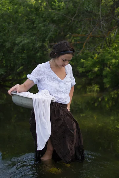 peasant woman washes clothes in the river