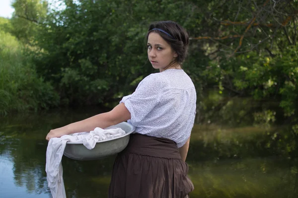 peasant woman washes clothes in the river