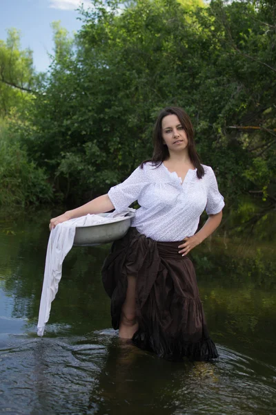 peasant woman washes clothes in the river