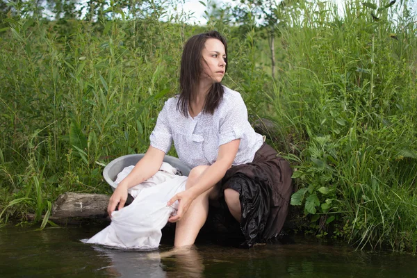 peasant woman washes clothes in the river