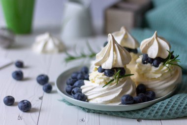 Beyaz ahşap arka planda yaban mersinli tatlı pavlova