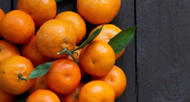 Kırsal ahşap masada taze organik mandalinalar.