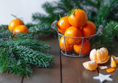 Ahşap bir arka planda metal bir sepetin içindeki mandalinalar.