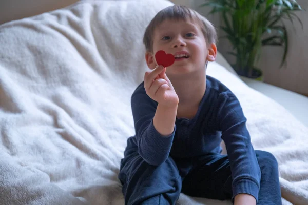 En liten pojke håller rött hjärta i handen — Stockfoto