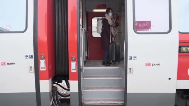 Kız valiz çantası taşıyan koruyucu bir tıbbi maske şehrin içine giriyor. Gera, Almanya. 16.01.2021 — Stok video