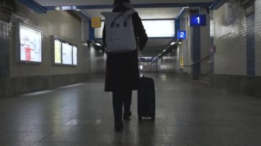  Tekerlekli bavullu bir kadın boş merkez tren istasyonundan trene doğru yürüyor..
