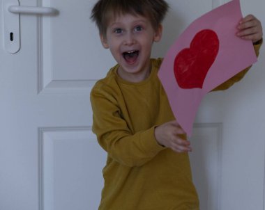 Elinde kalp resmi olan mutlu bir çocuk. Anneler Günü