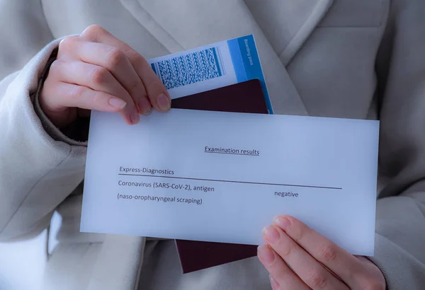 Elinde pasaport, biniş kartı ve koronavirüs testi olan bir kız.