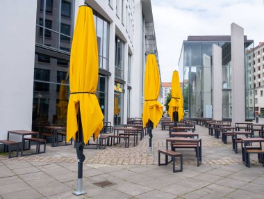 Cafe with tables and chairs, and lowered umbrellas on the streets of Dresden, Germany