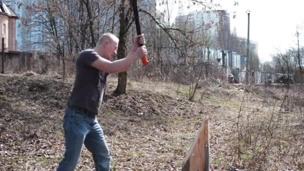 Un uomo con un'ascia che taglia legna — Video Stock